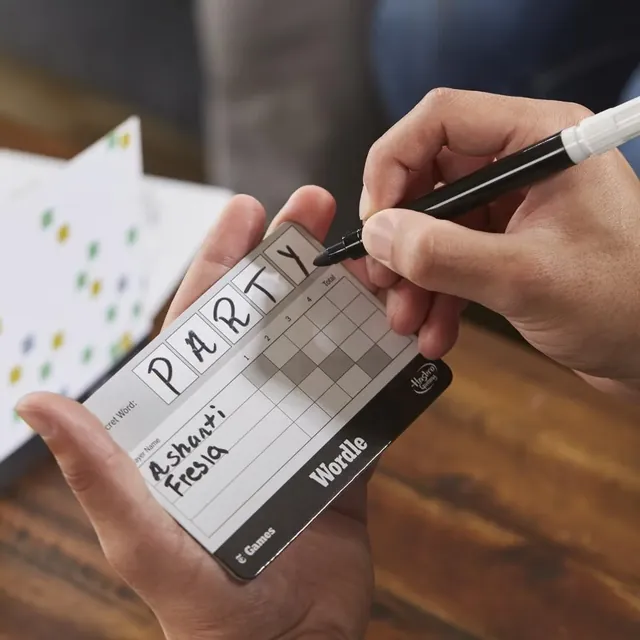 A hand writing PARTY on a Secret Word board with a marker