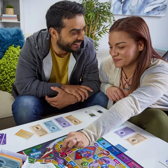 A man and a woman moving their cars along the board