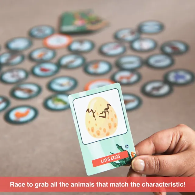 A hand holding a 'lays eggs' card above a spread of animal tokens: race to grab all the animals that match