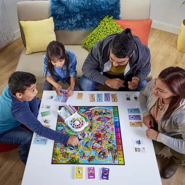 A family of four playing The Game of Life around a low table