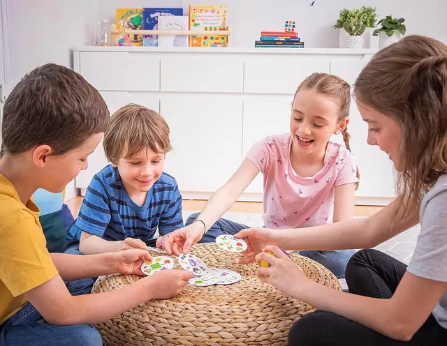 Four children playing Dobble on a woven rug