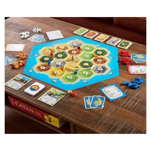A game in progress on a wooden coffee table: the island board with roads and settlements, cards and pieces around it, and the Catan box on the shelf below