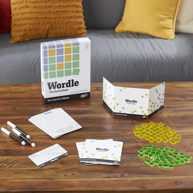The Wordle box, boards, shields, markers and tiles on a wooden table