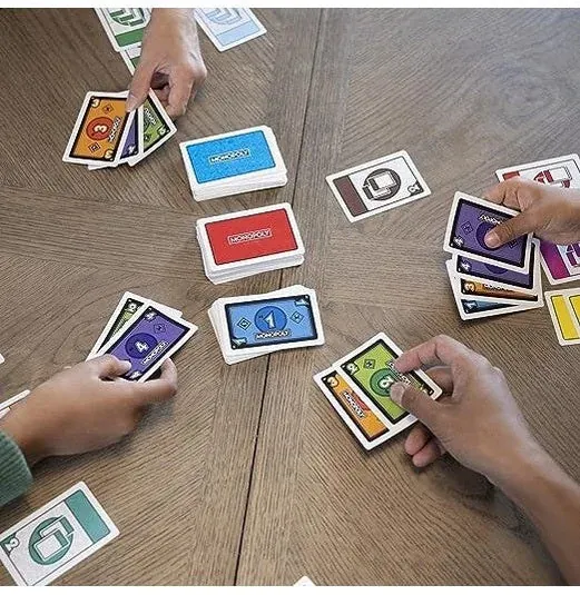 Hands holding and laying down Monopoly Bid cards on a wooden table