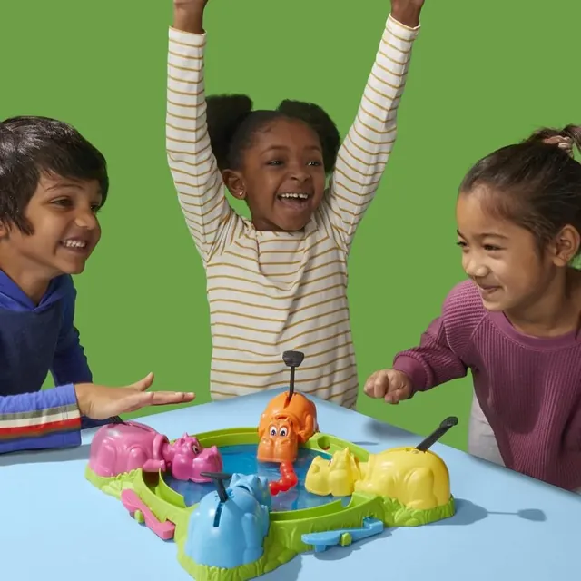 Three children around the game, one cheering with both arms up